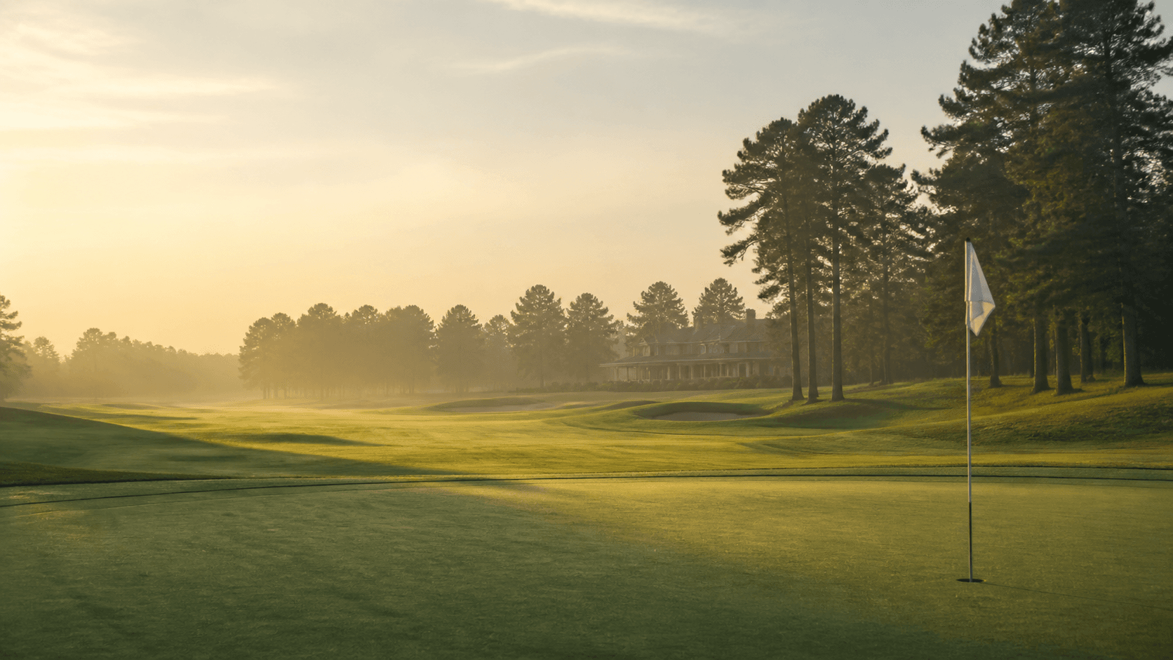 An early-morning golf course with a flag beside the green